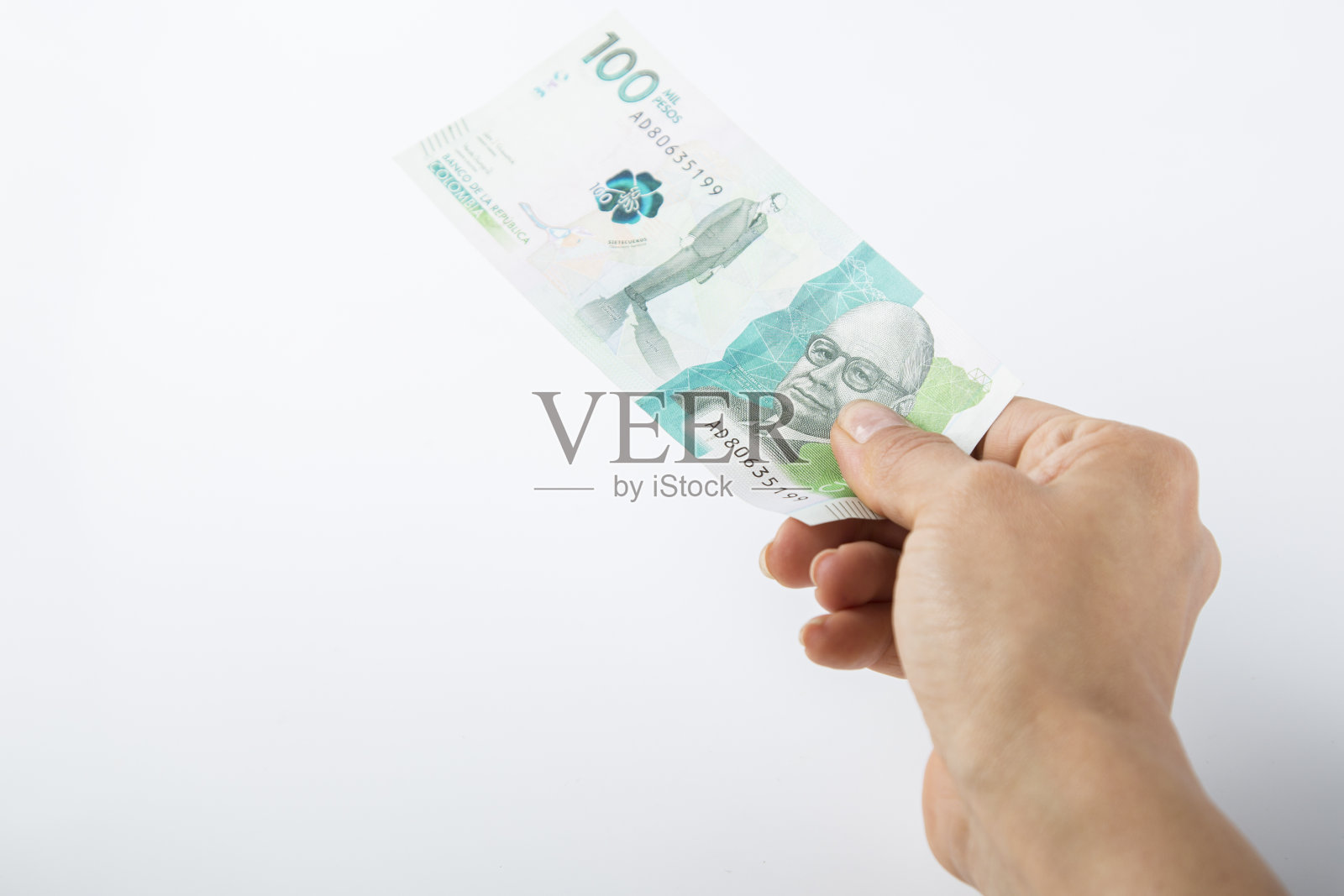 一个人递上一张十万哥伦比亚比索的钞票照片摄影图片