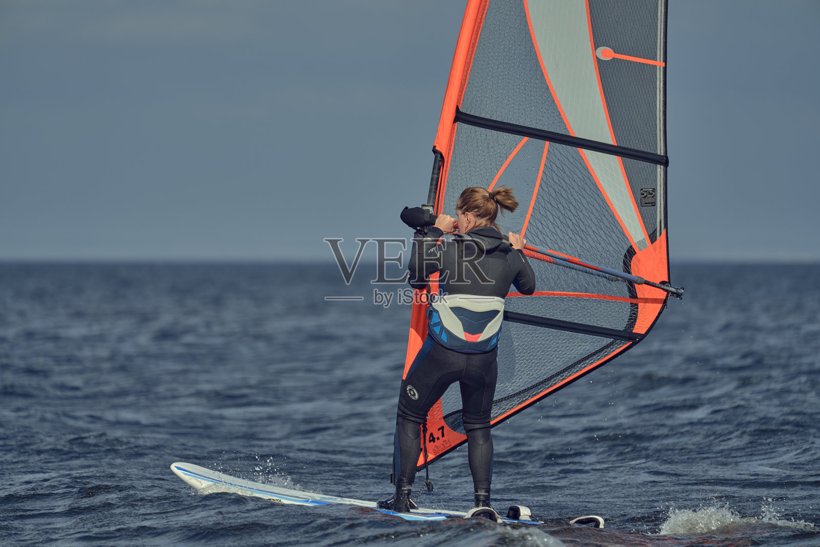 成熟女子冲浪初学者在帆板上慢慢移动。照片摄影图片