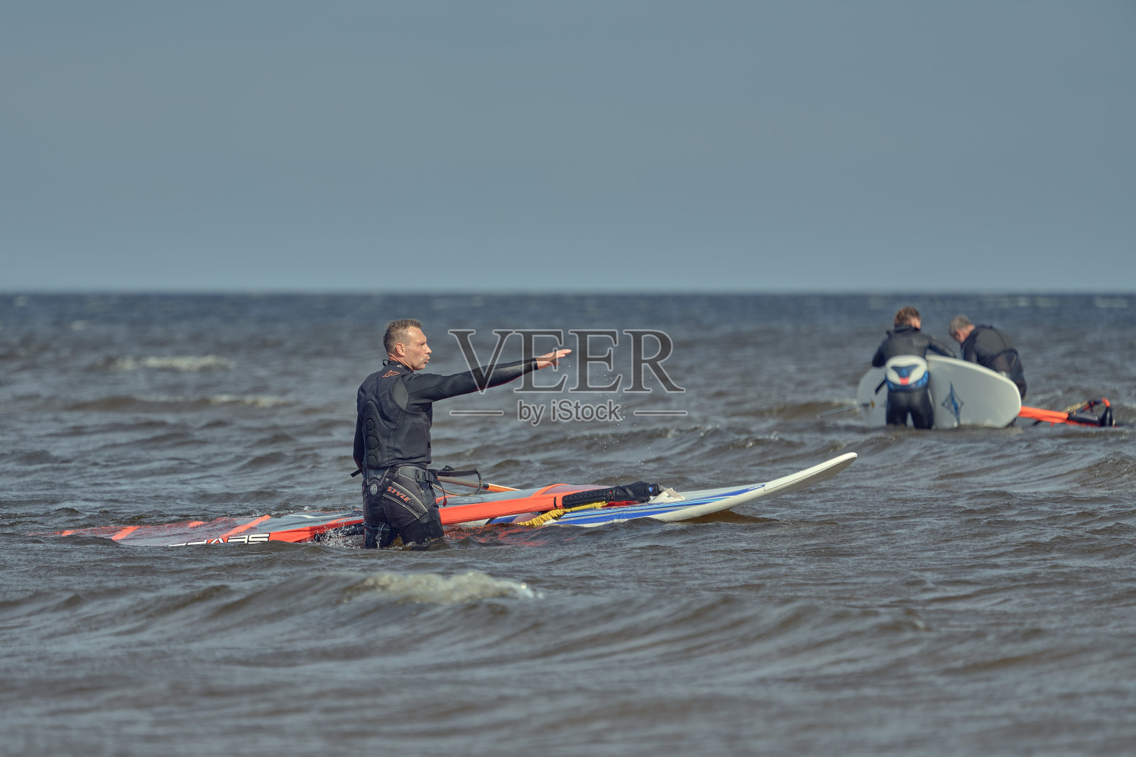 帆板运动员站在浅水里。照片摄影图片
