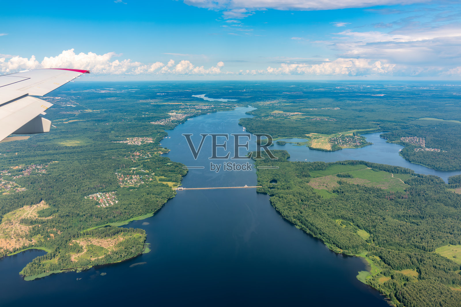 飞机着陆时，可以看到机翼、蓝天、绿地和河流。飞机窗口视图。照片摄影图片