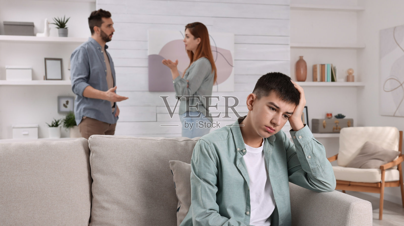 夫妻在家里吵架，把注意力放在他们不开心的少年身上。家庭问题照片摄影图片