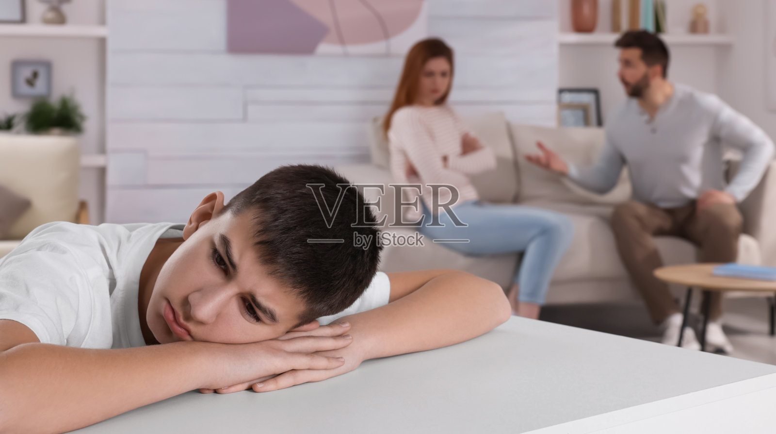 夫妻在家里吵架，把注意力放在他们不开心的少年身上。家庭问题照片摄影图片