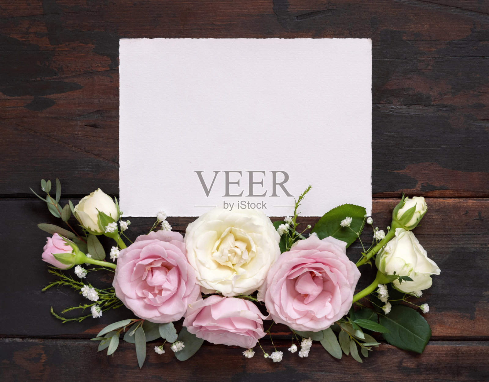 水平卡之间的粉红色和奶油玫瑰在棕色的木材顶视图，婚礼的模型照片摄影图片