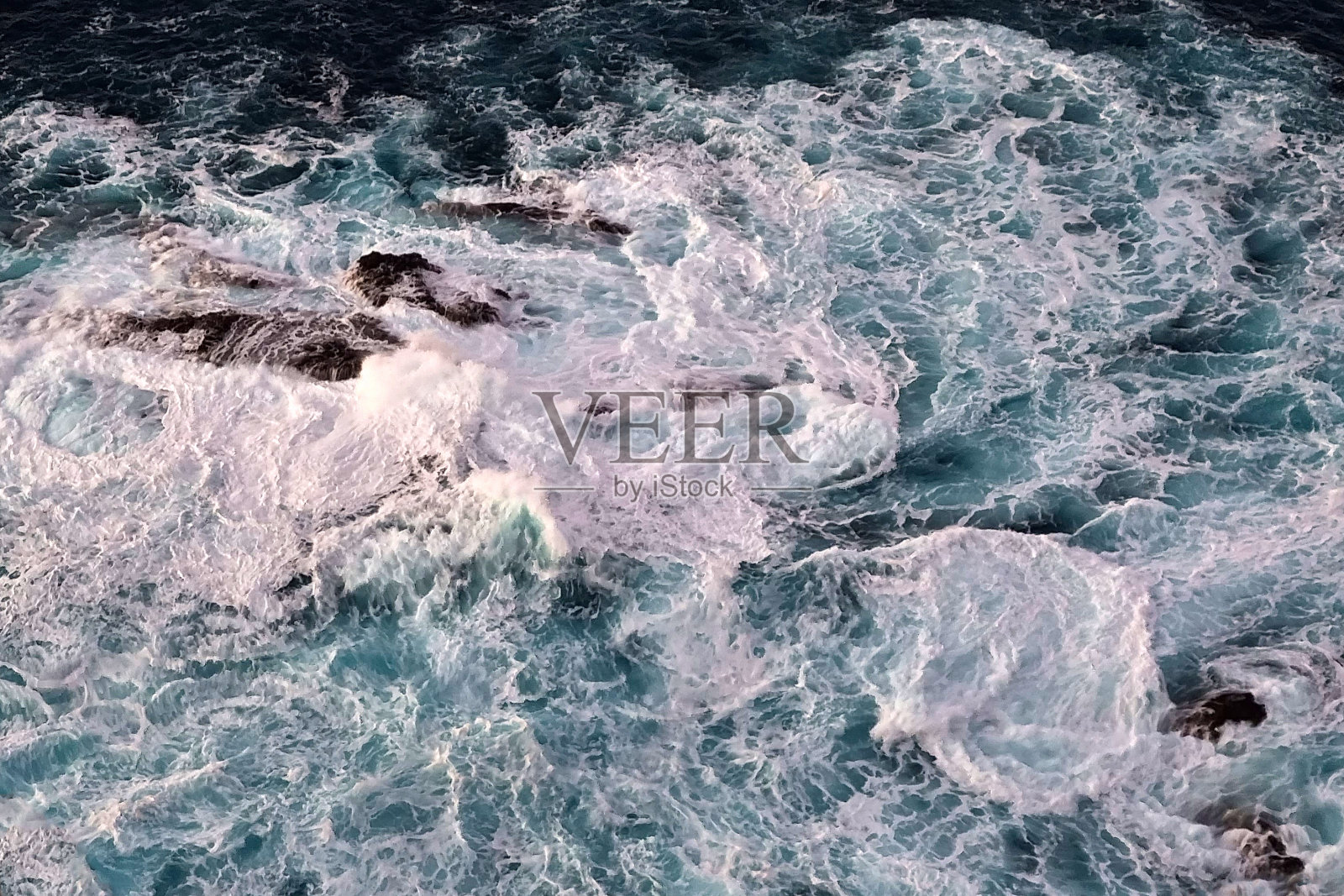 海浪拍打在岩石上的泡沫。自然的背景。青绿色的水。照片摄影图片