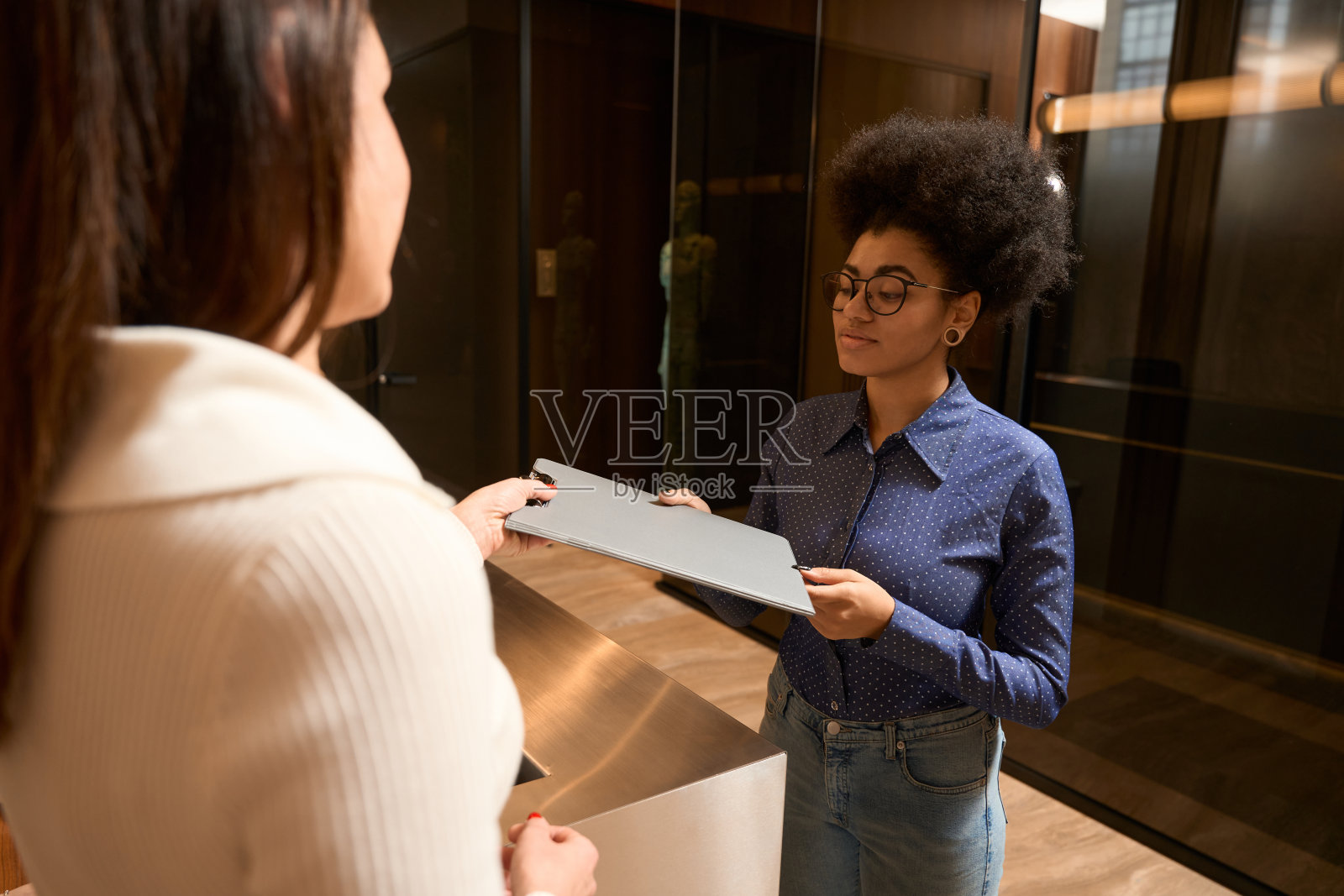 漂亮的非裔美国女性在前台拿文件照片摄影图片
