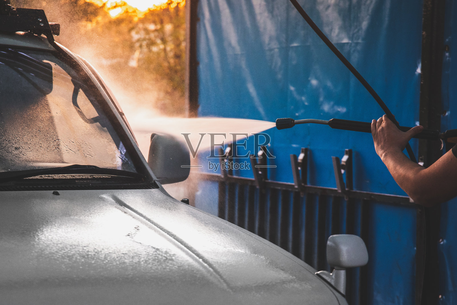 人手洗白色汽车上的无接触式自助洗车水射流。用高压水洗车照片摄影图片