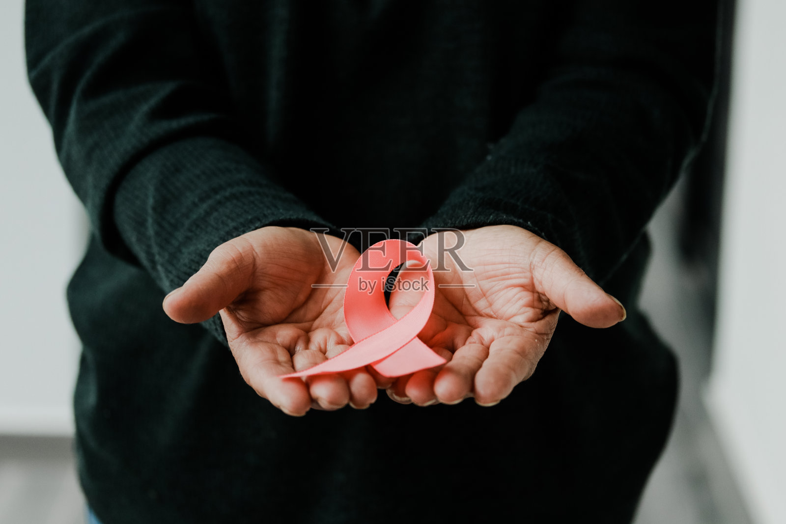 女人的手拿着粉红色或紫色的丝带。照片摄影图片