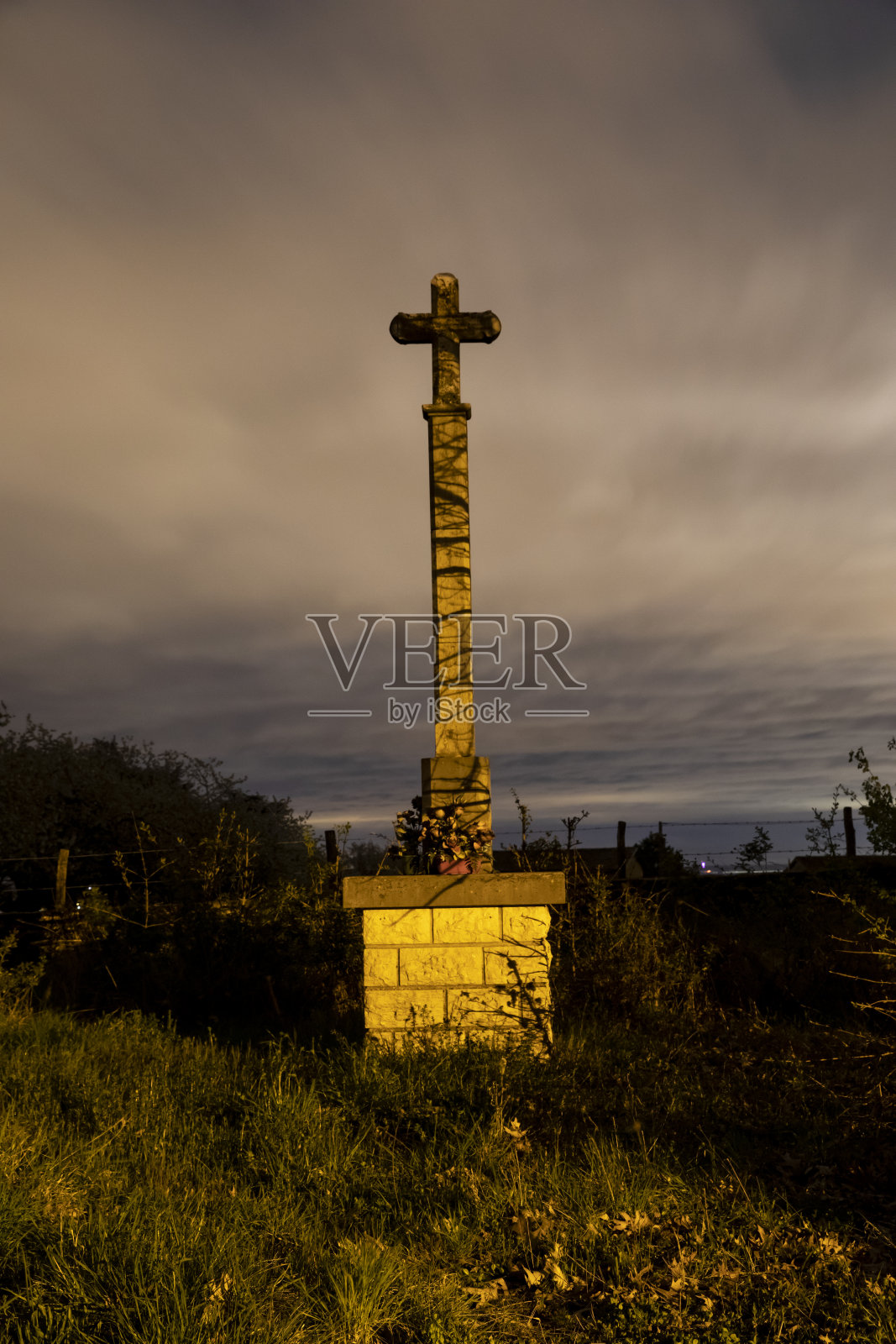 在一个风景优美的夜晚，一个十字雕像在田野里的垂直镜头照片摄影图片