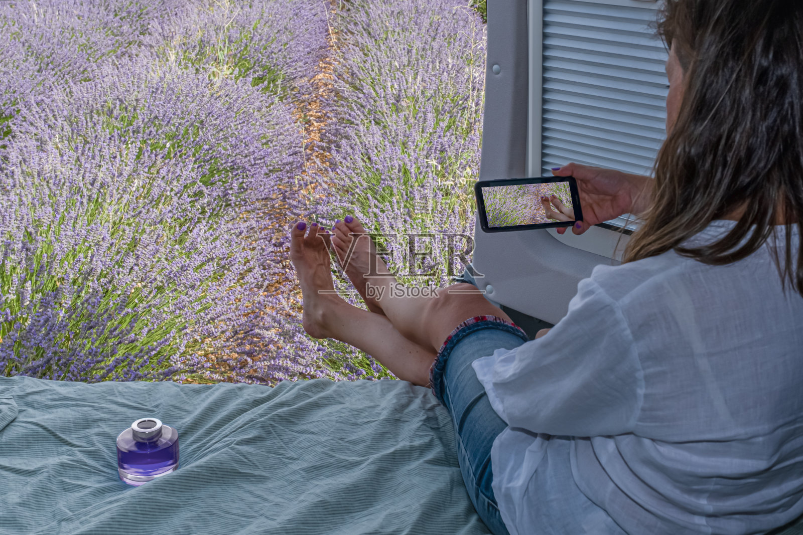 一名女子在一辆大篷车里拍摄田地里的薰衣草花照片摄影图片