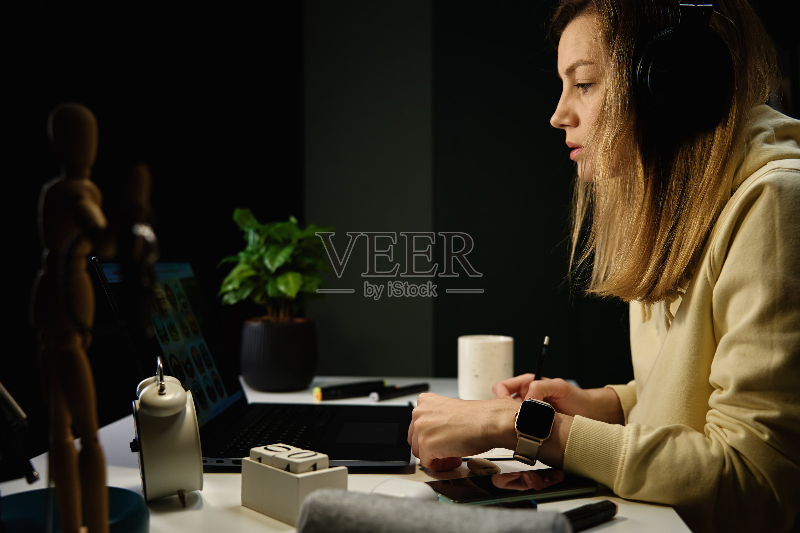 女人晚上戴着耳机听音乐，用笔记本电脑照片摄影图片