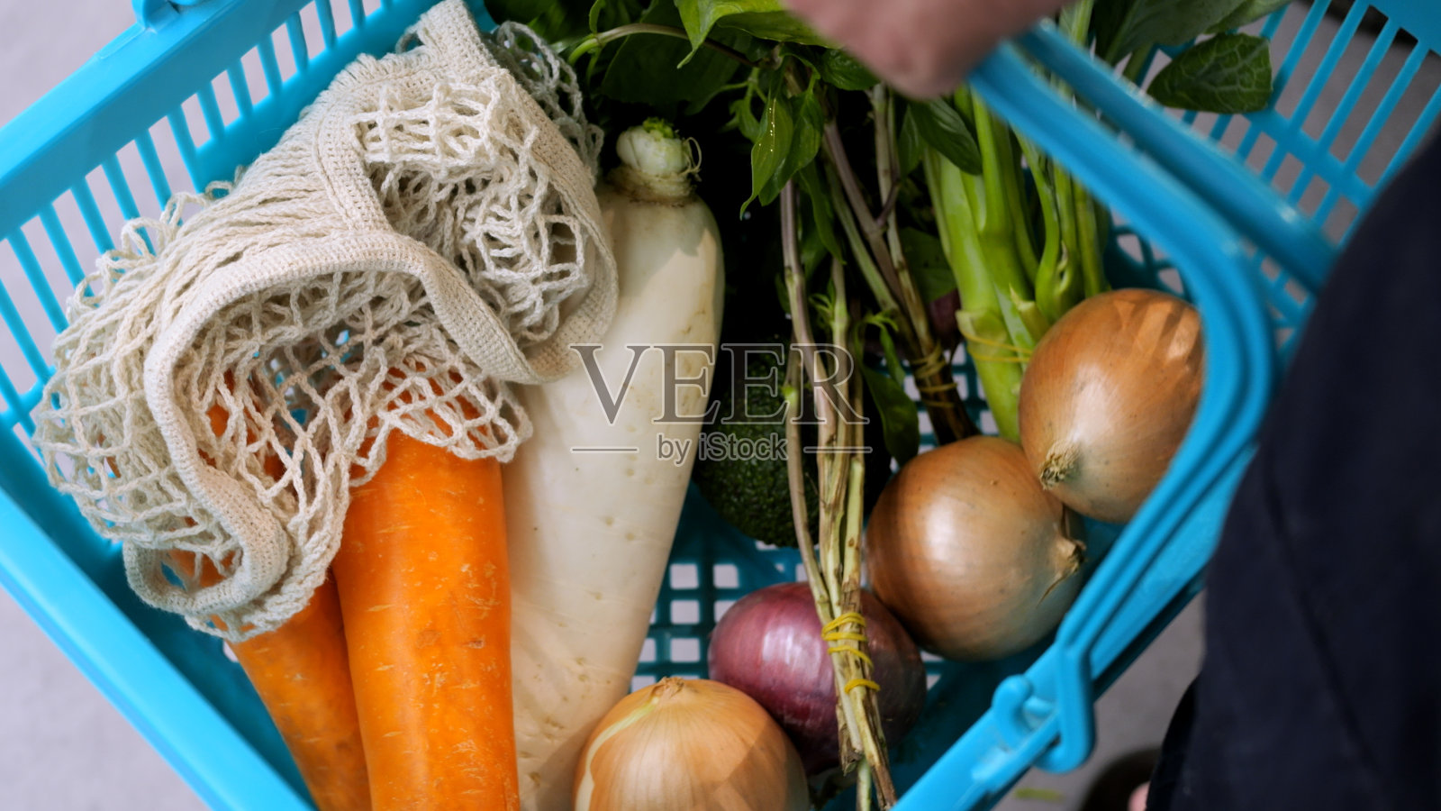 买家手里拿着装满蔬菜的购物篮，俯视图。有能力从环保商店买到新鲜蔬菜和水果的消费者。有机蔬菜购物车照片摄影图片
