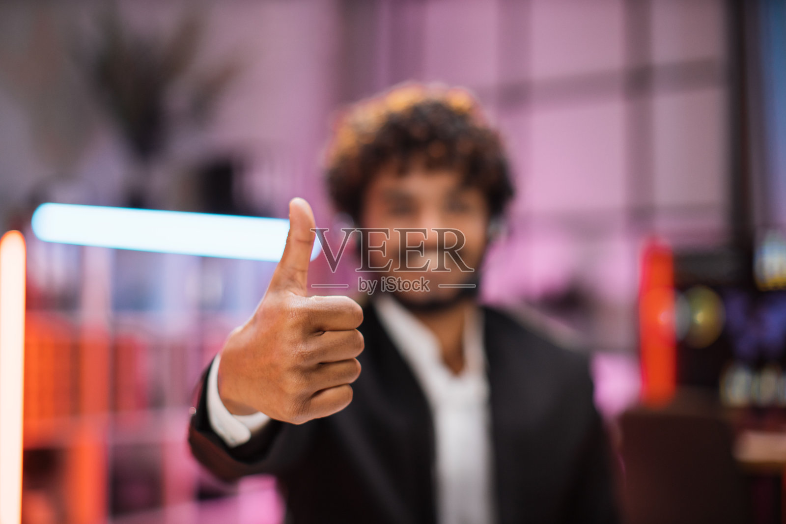 穿着正装，头戴耳机，面带微笑，积极自信，坐在办公桌前照片摄影图片