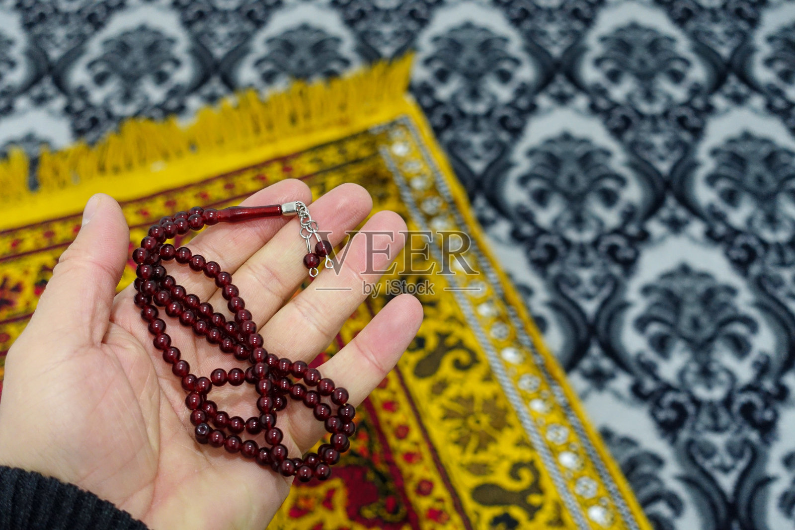 近距离的念珠和祈祷毯，祈祷是在清真寺的祈祷毯上进行的，照片摄影图片
