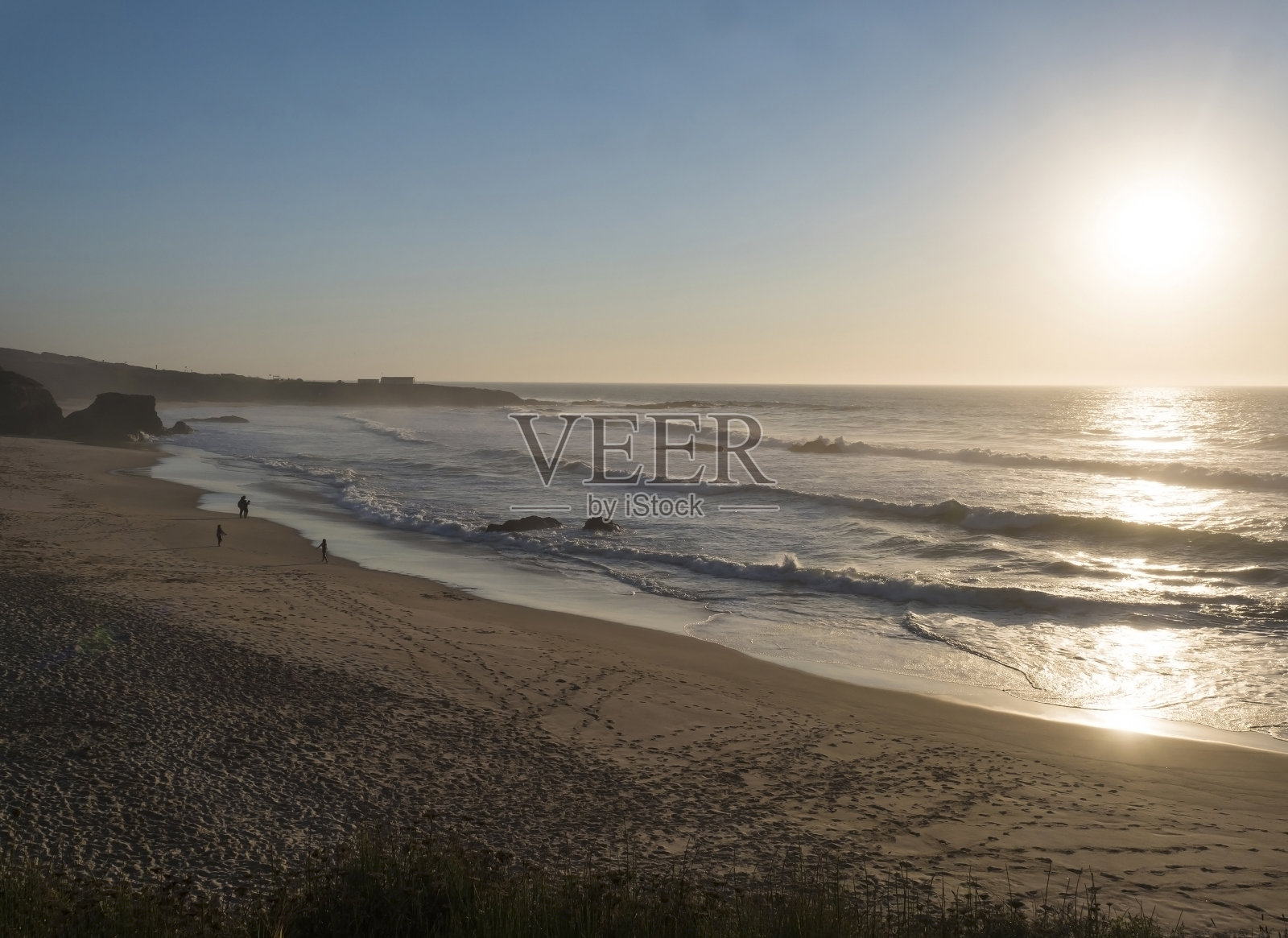 普拉亚·格兰德·阿尔莫格雷夫沙滩，在黄金时辰的灯光下，远处的人群和海浪，湛蓝的天空。葡萄牙阿尔莫格雷夫的Rota Vicentina海岸照片摄影图片