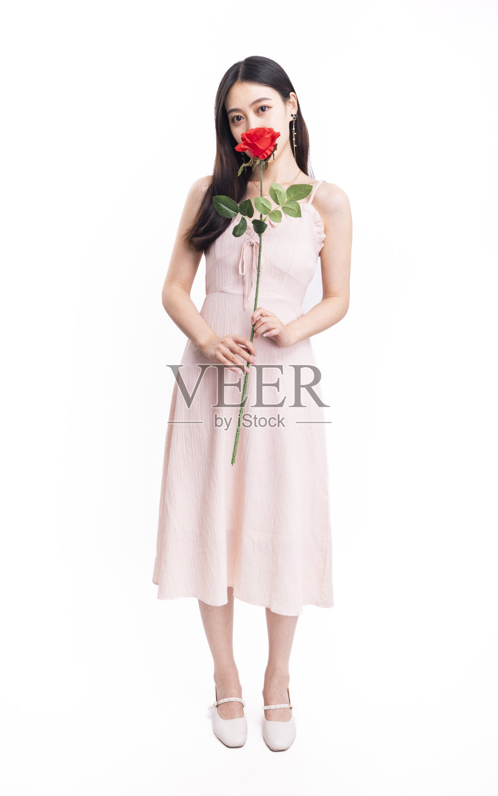 一个穿着粉红色连衣裙，戴着红玫瑰的女孩照片摄影图片