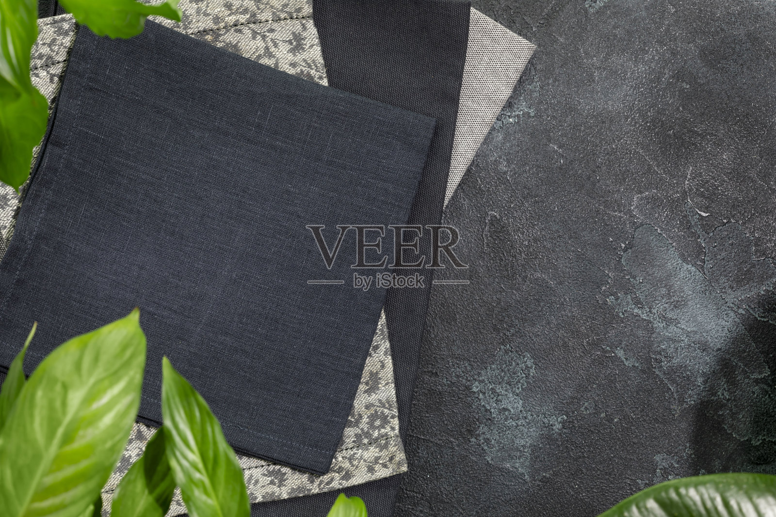 黑色的餐巾在黑色的背景与绿色的叶子和复制空间照片摄影图片