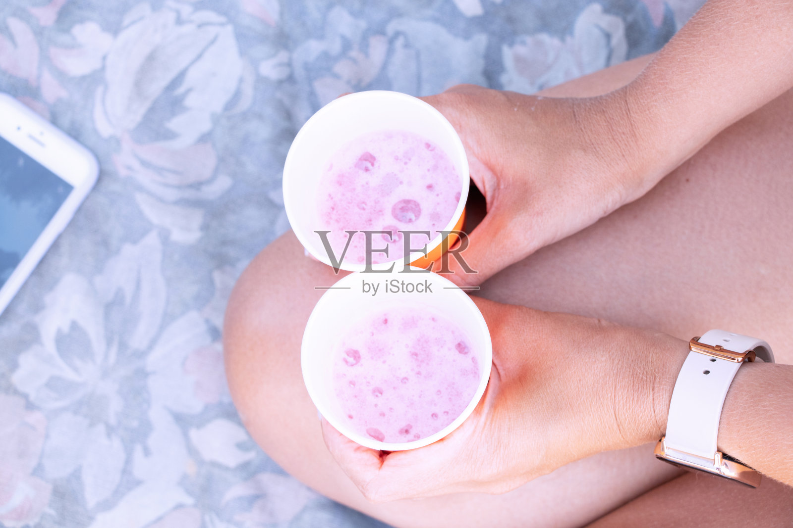 这个女孩手里拿着两个一次性玻璃杯，里面装着度假时在海滩上玩的酒，杯子里装着香槟照片摄影图片