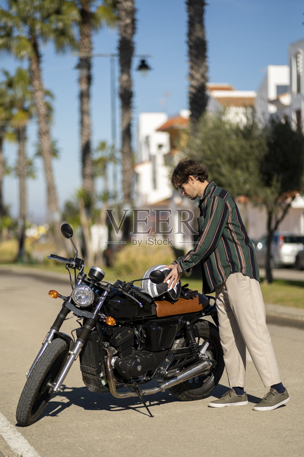 帅哥靠近摩托车司机摆着花哨的衣服照片摄影图片