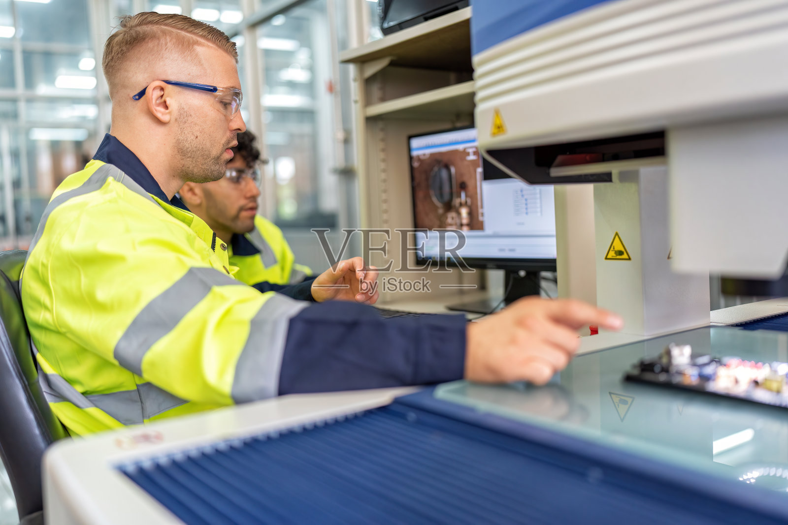 工程师坐在机器人制造室使用测量显微镜检查电子板照片摄影图片