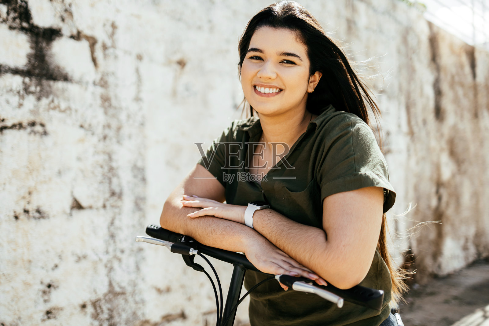 在城市里骑自行车的微笑女人的肖像照片摄影图片
