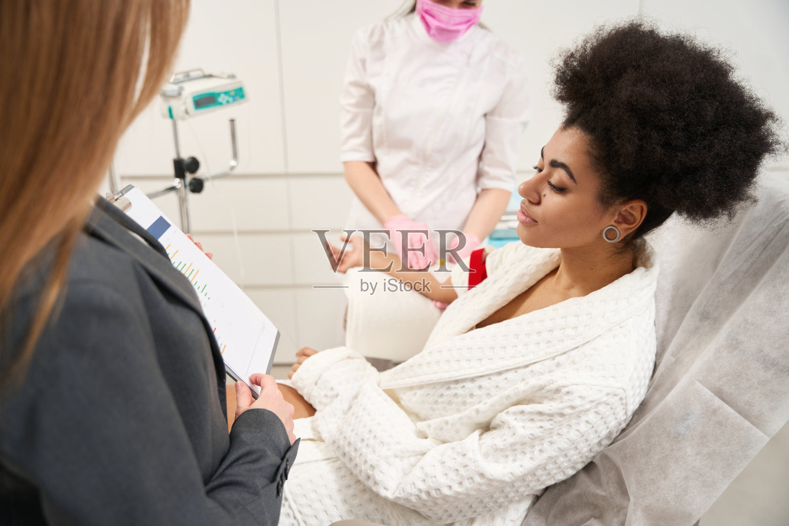 漂亮女人在医院治疗期间读文件照片摄影图片