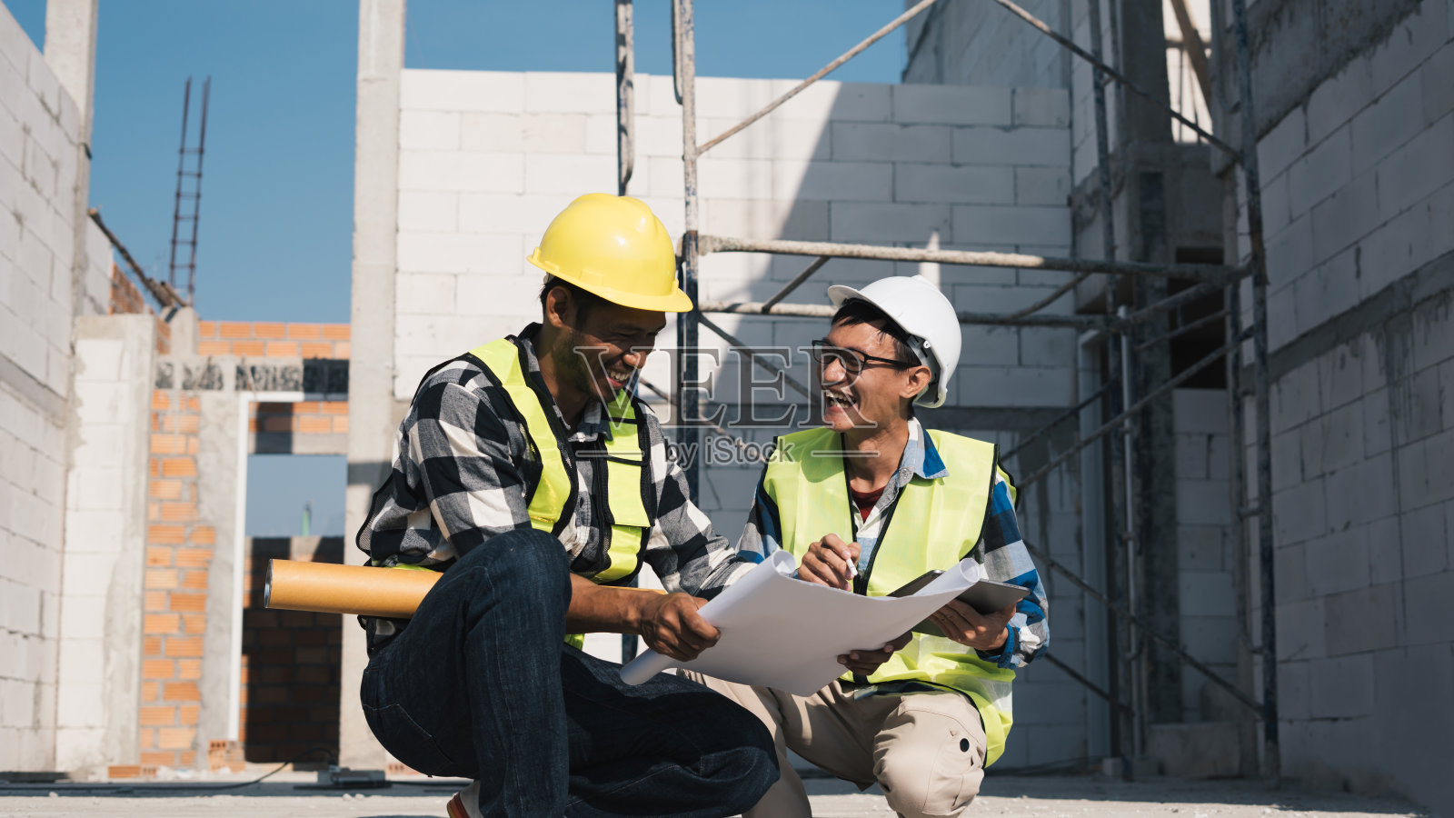 结构工程师和建筑师在户外施工现场讨论蓝图。照片摄影图片