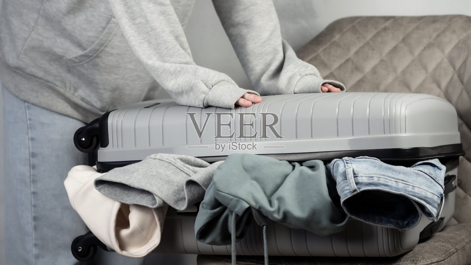 行李箱包装衣物。一位年轻女子正把她的东西装进一个大手提箱。旅行准备概念。照片摄影图片