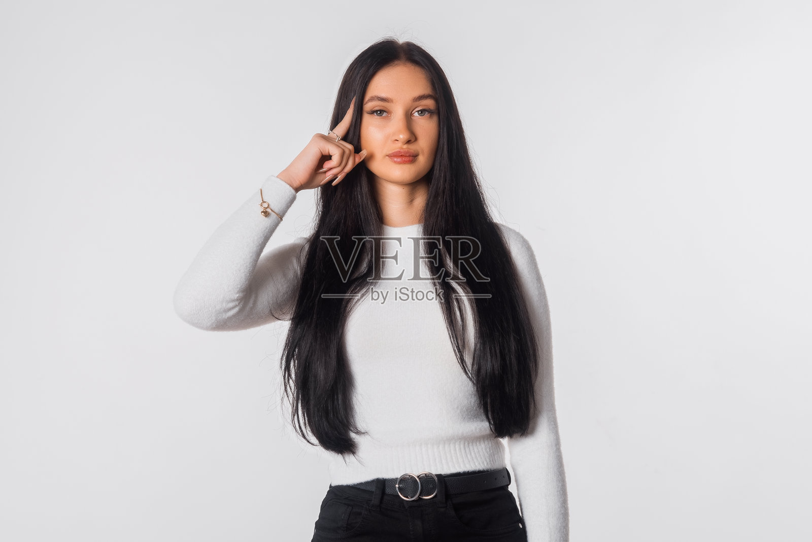 年轻认真和自信的黑发女子，看起来深思熟虑，有一个想法，站在便服白色背景。漂亮女孩想。情绪和肢体语言的概念照片摄影图片