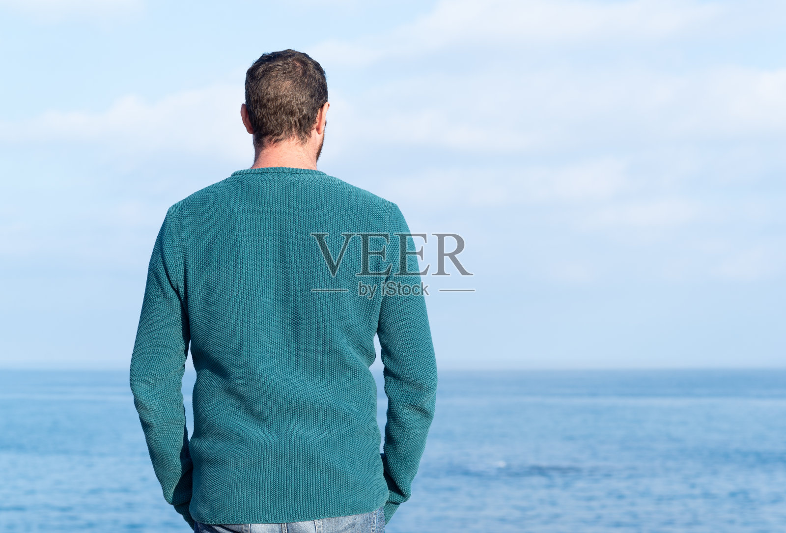 一个男人看着大海的背影。照片摄影图片