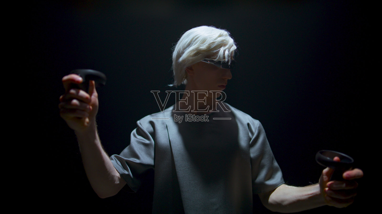 在暗室中使用控制器的Vr播放器。专注的男人手势体验照片摄影图片