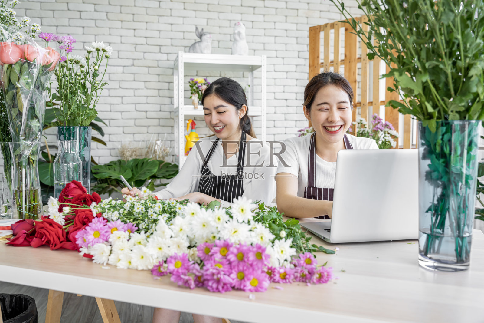 亚洲人正在为前来订购鲜花参加婚礼、情人节或送给爱人等各种仪式的顾客插花。照片摄影图片