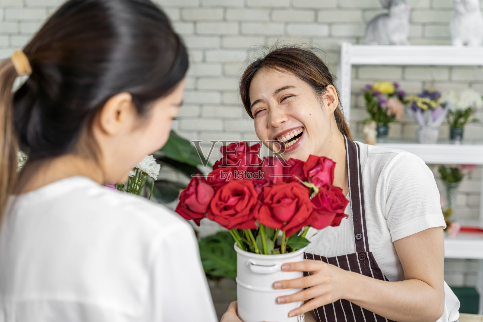 亚洲人正在为前来订购鲜花参加婚礼、情人节或送给爱人等各种仪式的顾客插花。照片摄影图片