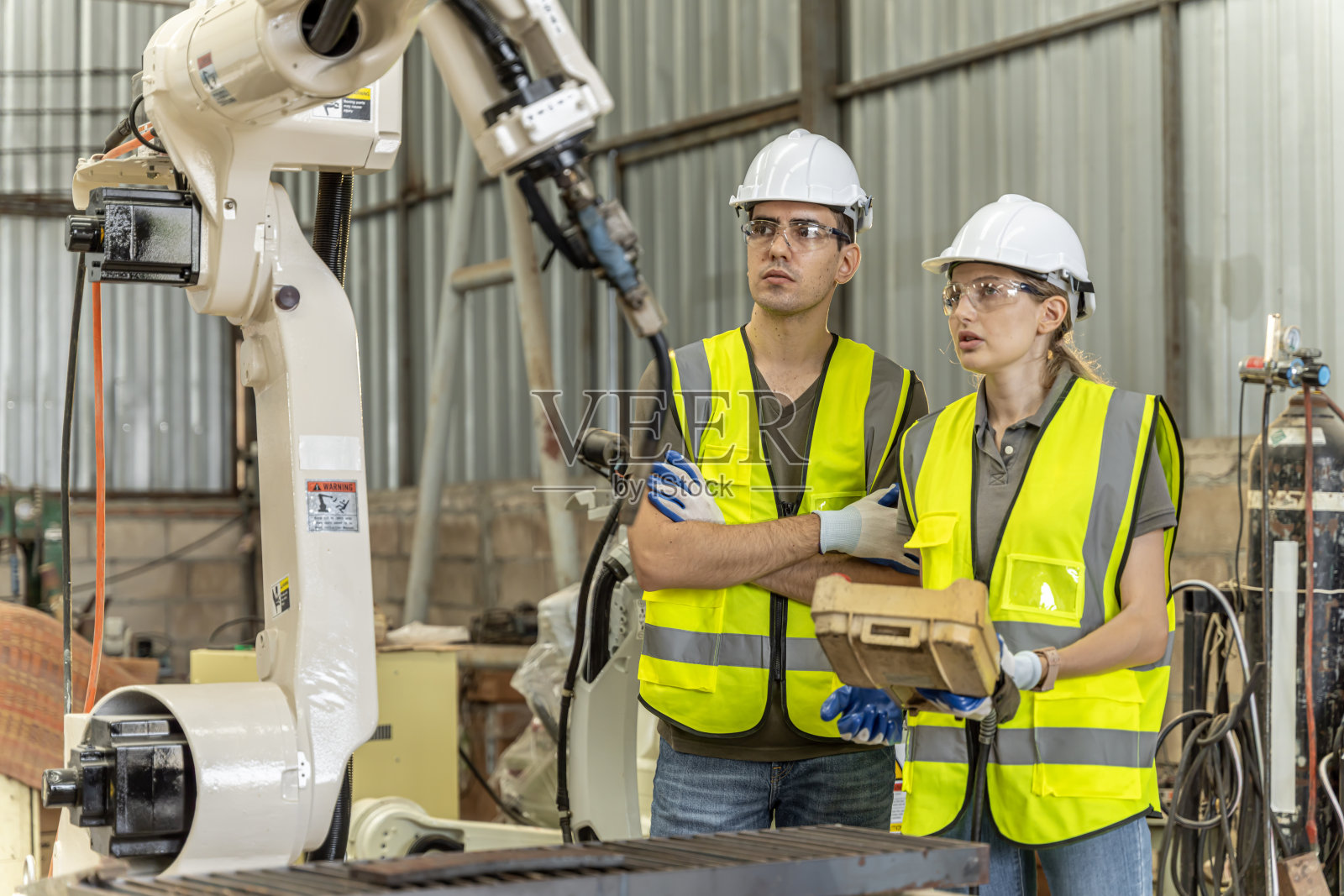 一组男女工程师开会检查电脑控制的钢铁焊接机器人。计划排练和安装使用。照片摄影图片