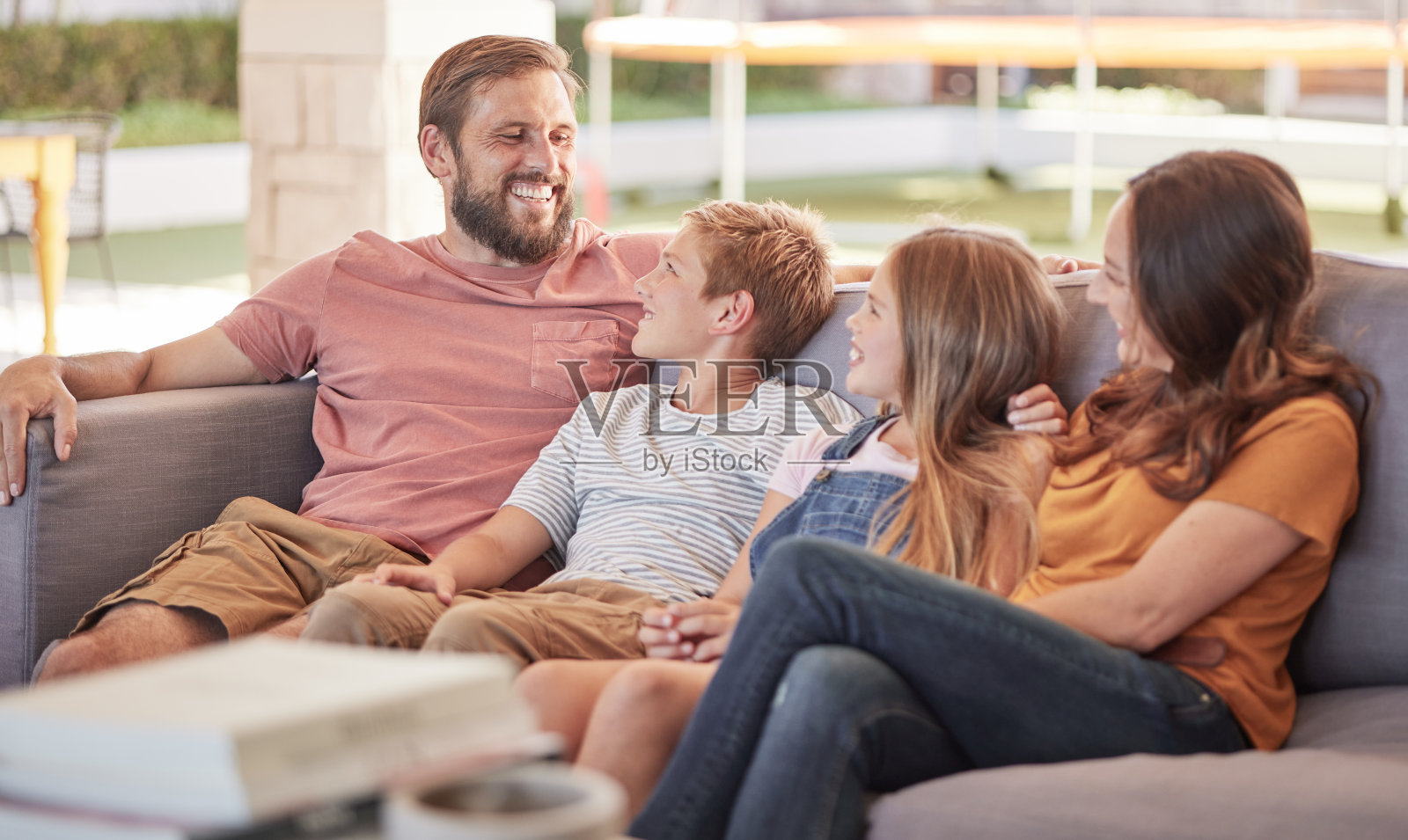 幸福的一家人，坐在沙发上一起放松，笑着笑着开玩笑，幸福的坐在家里。父亲，母亲和年幼的孩子在沙发上与纽带，喜剧和爱在休息室在度假屋照片摄影图片