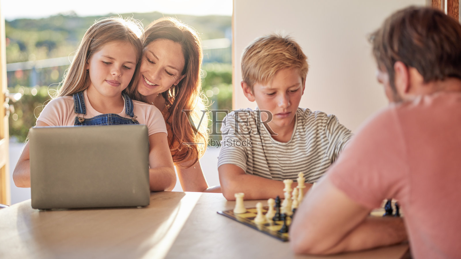 家庭，父母和孩子带着笔记本电脑，下棋和学习一起在家里玩，教育和联系。爸爸，孩子和棋盘游戏的思想，战略和发展与pc，母亲和女儿照片摄影图片