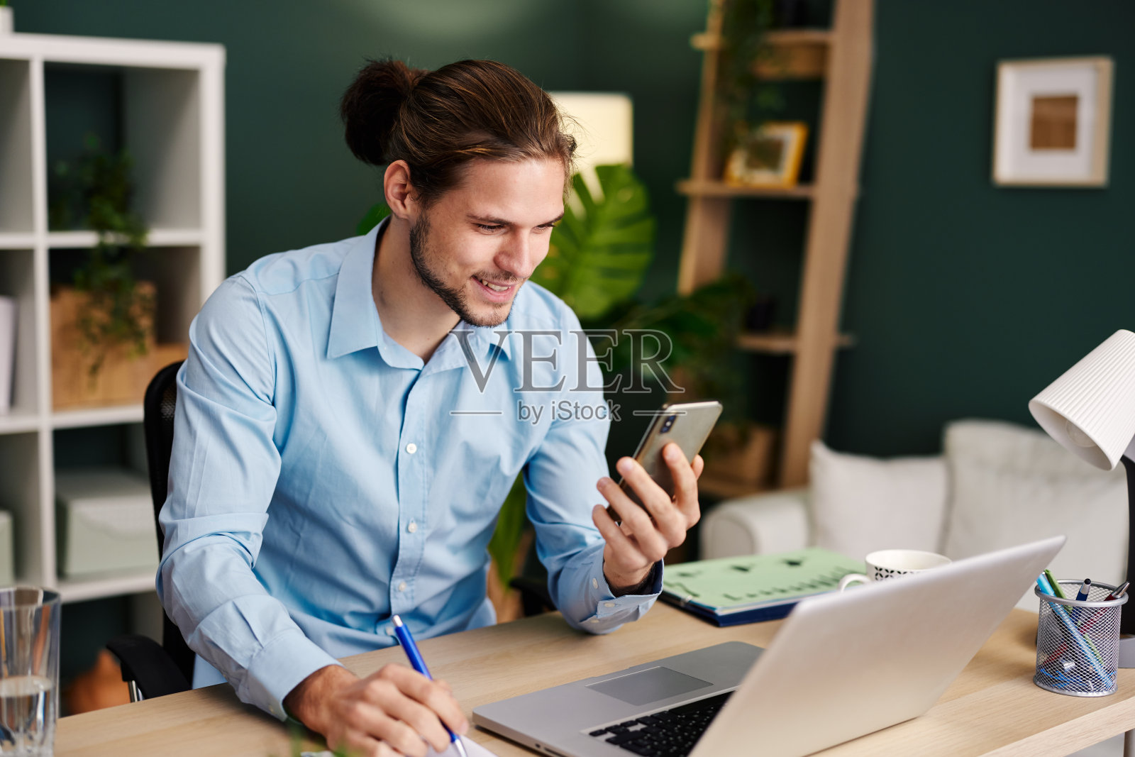 年轻快乐的男子在家庭办公室用智能手机进行视频通话照片摄影图片