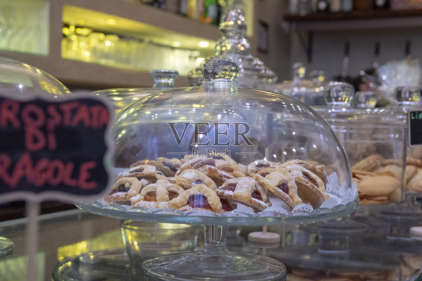 柜台上的玻璃钟下有自制的饼干和馅饼照片摄影图片