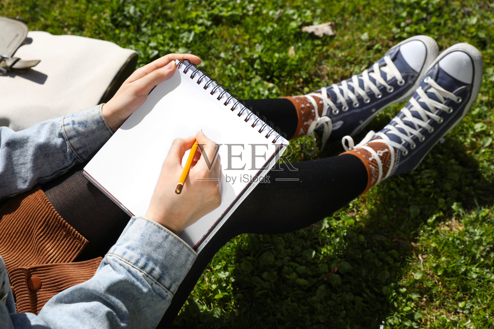女人在户外的绿色草地上画速写本，特写照片摄影图片