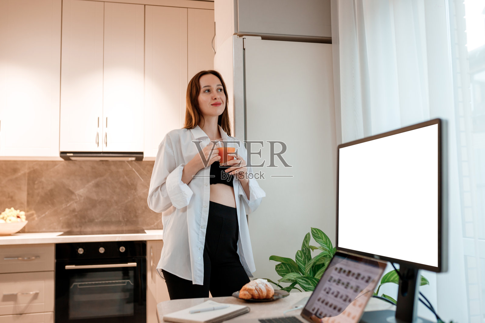 快乐微笑的女人在家里的厨房喝果汁。健康生活理念照片摄影图片