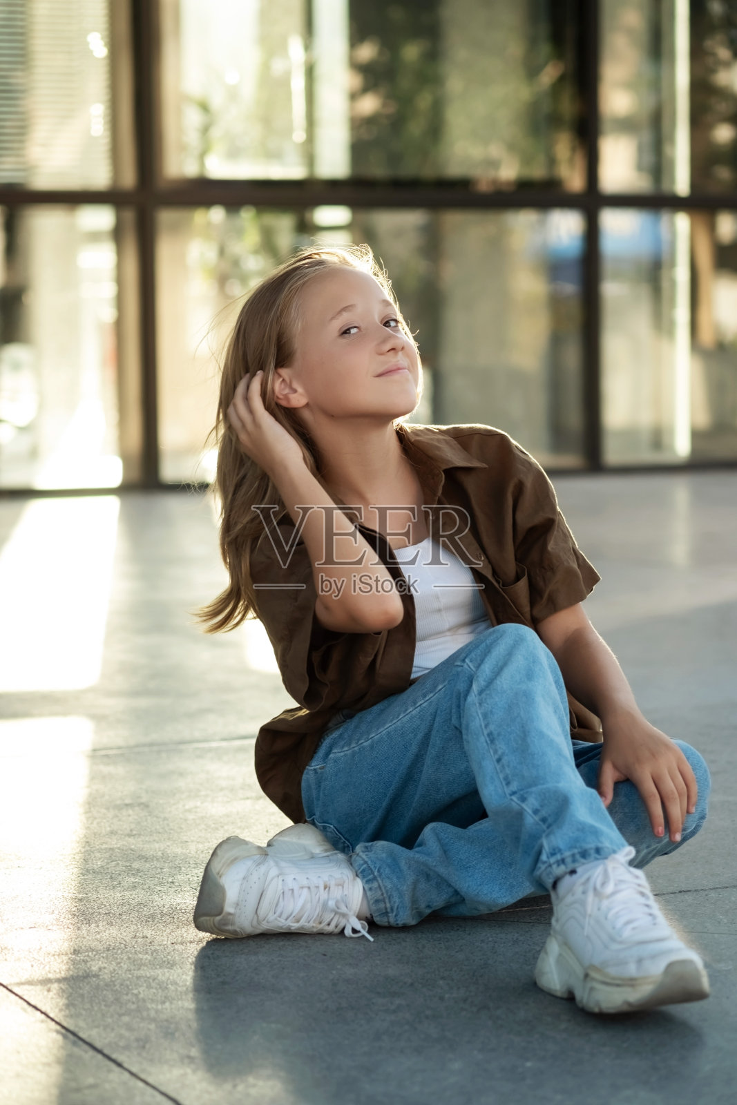 十几岁女孩坐在地板上的肖像，城市街道，阳光照片摄影图片