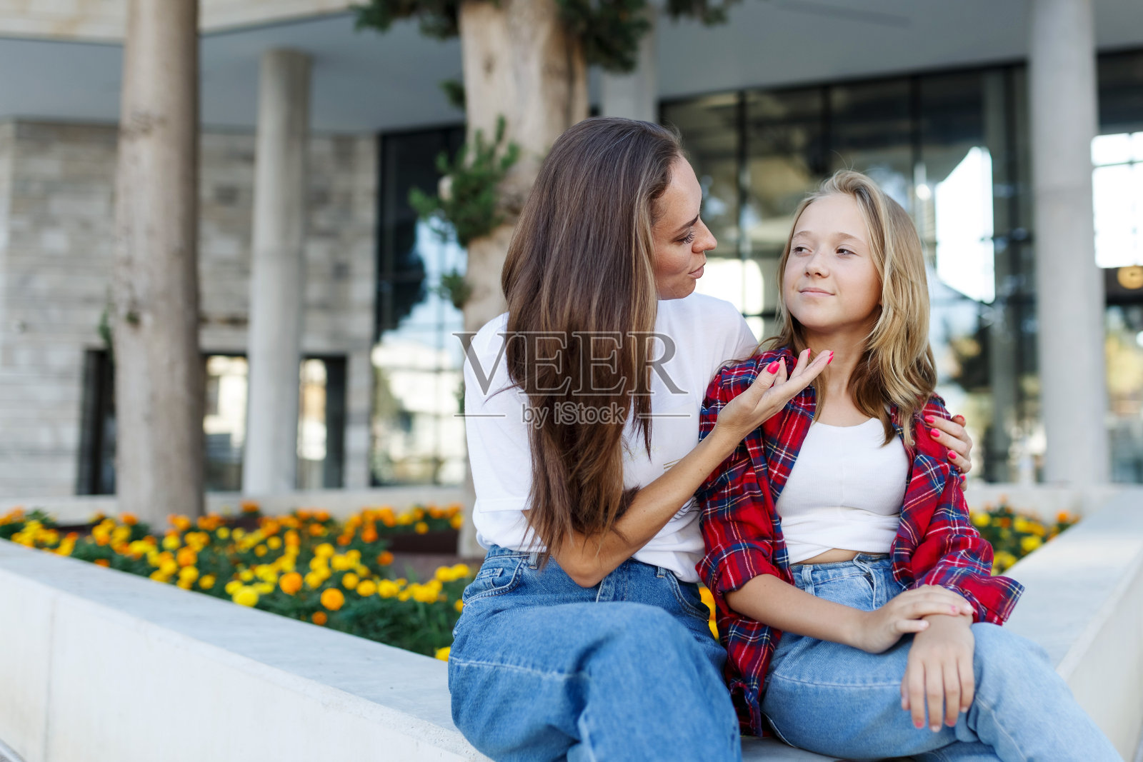 女人坐在外面和女学生女儿聊天。开朗的少女说话和拥抱母亲的好心情。爱与家庭概念照片摄影图片