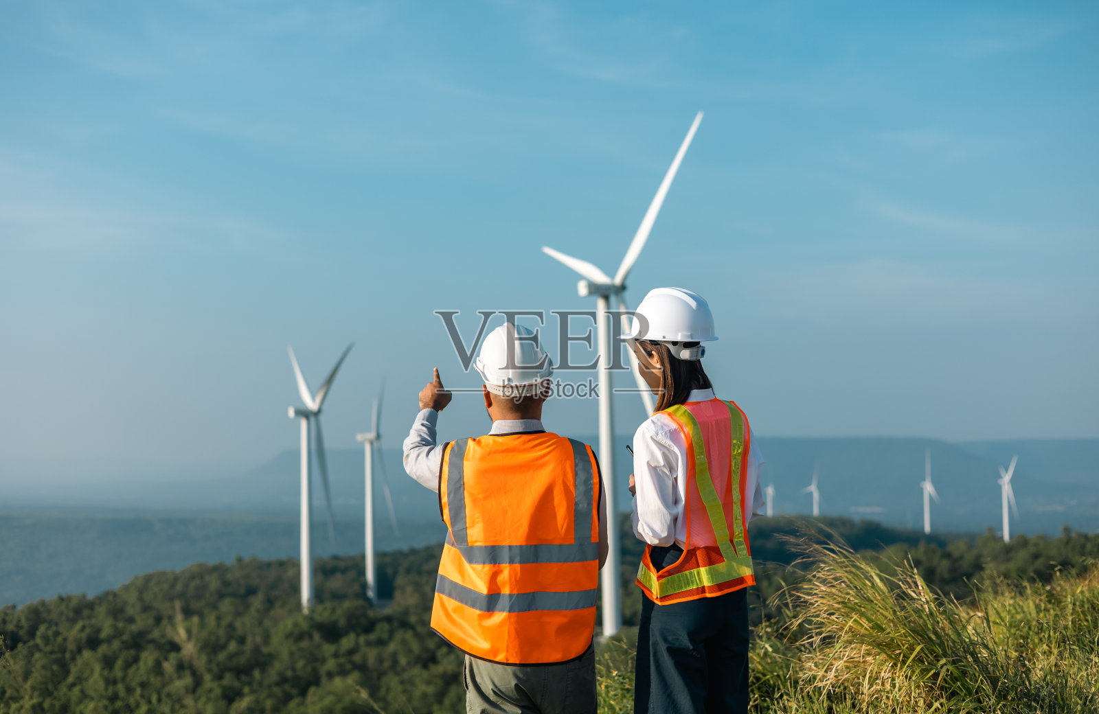 两名工程师在风车农场工作，生产电力和清洁能源。风力发电机是一种绿色替代能源。亚洲工程师检查控制电力照片摄影图片