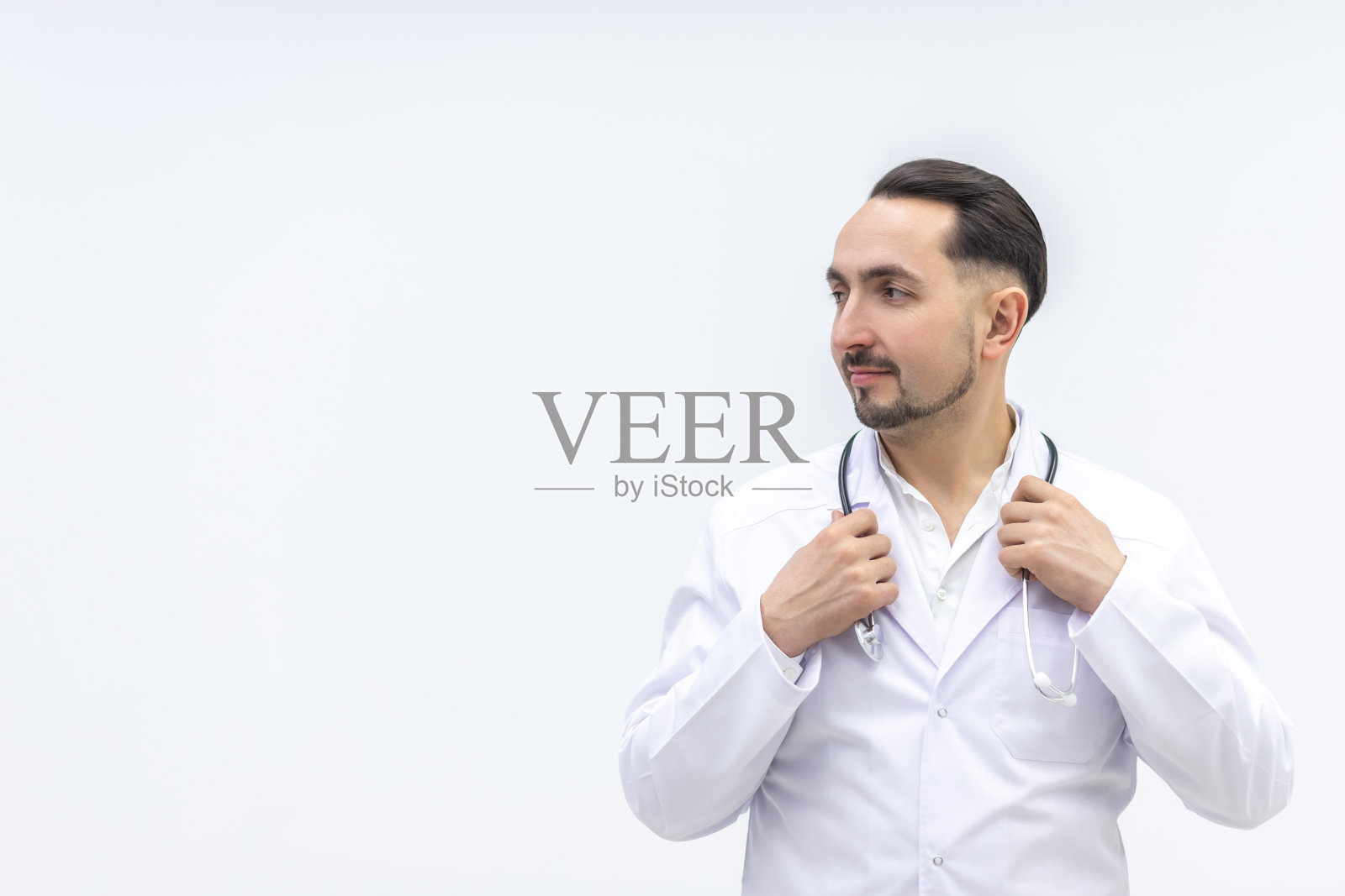 照片男性成熟医生摆姿势在相机与听诊器。照片摄影图片