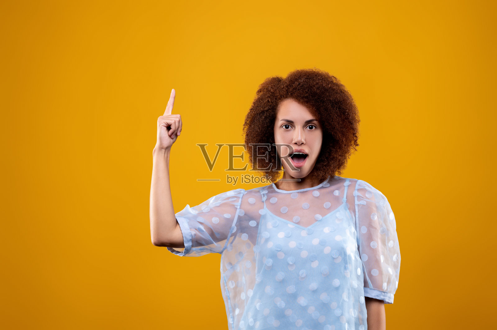 穿着白衬衫的可爱年轻女子，手指向上照片摄影图片