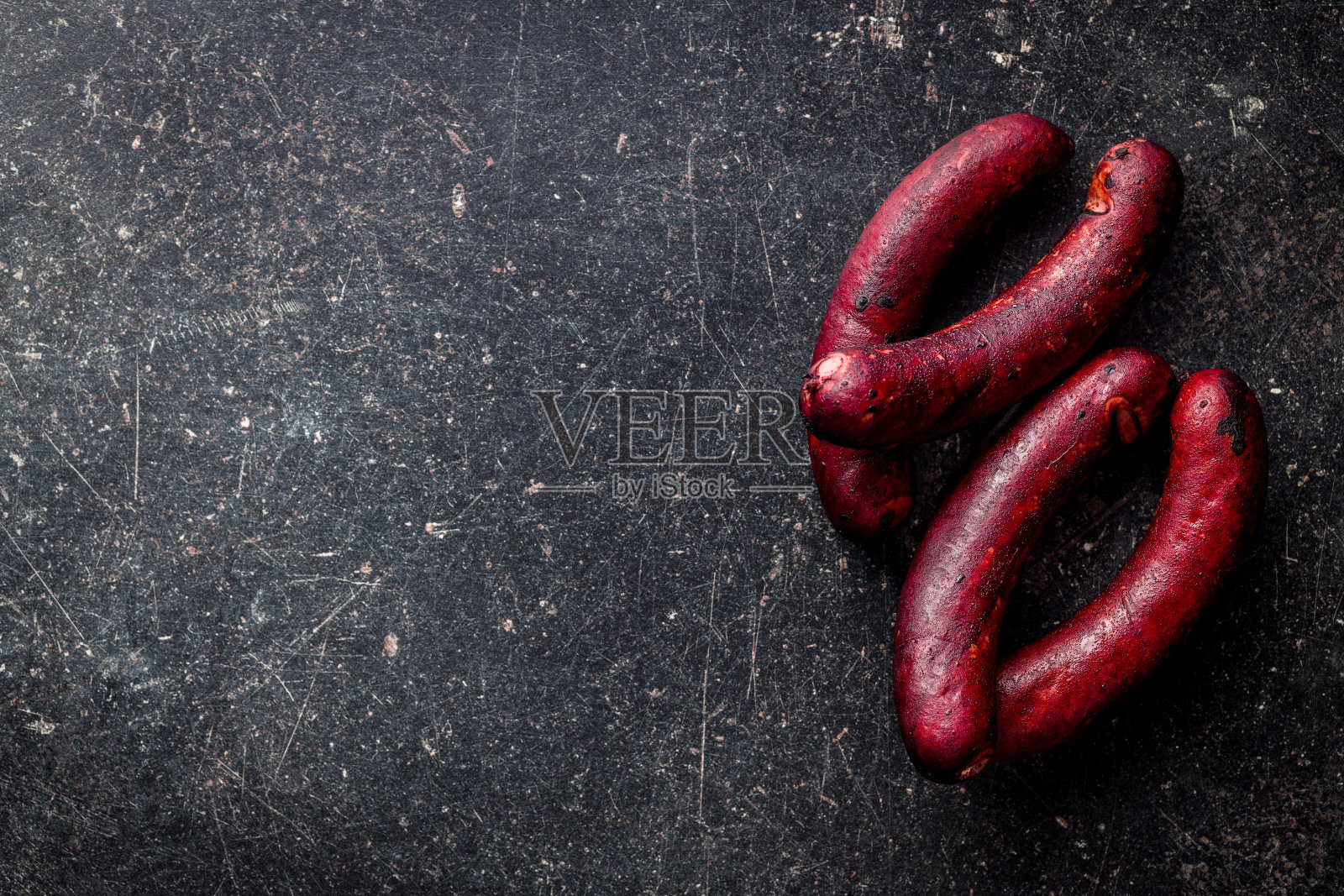 黑桌子上的烟熏猪肉香肠。照片摄影图片