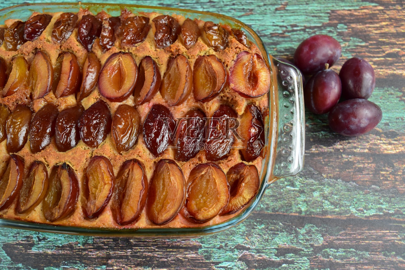 新鲜出炉的李子蛋糕放在绿色木板上照片摄影图片