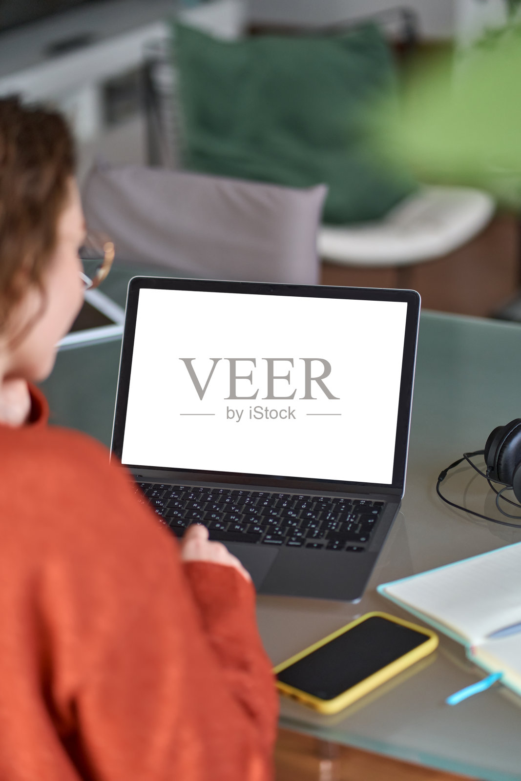 女子电子学习看着模拟屏幕使用笔记本电脑，越过肩膀，垂直。照片摄影图片