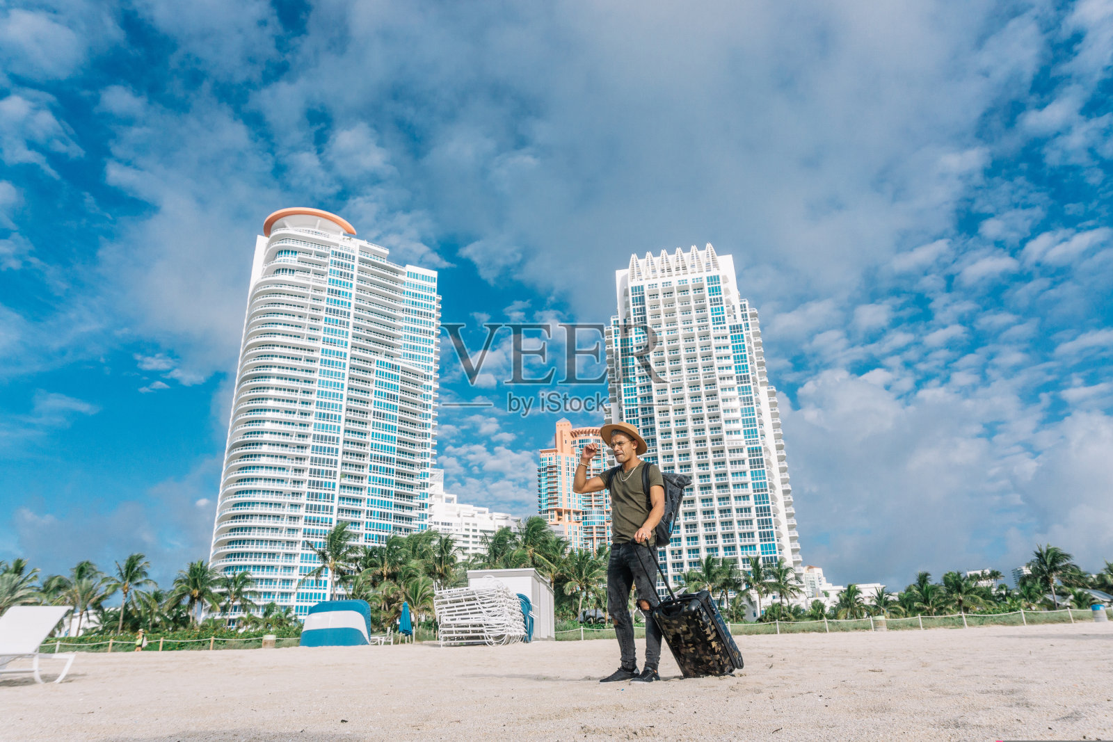 迷人的年轻人在一个阳光明媚的暑假，建筑户外背景。在沙滩上享受阳光的旅行方式。照片摄影图片