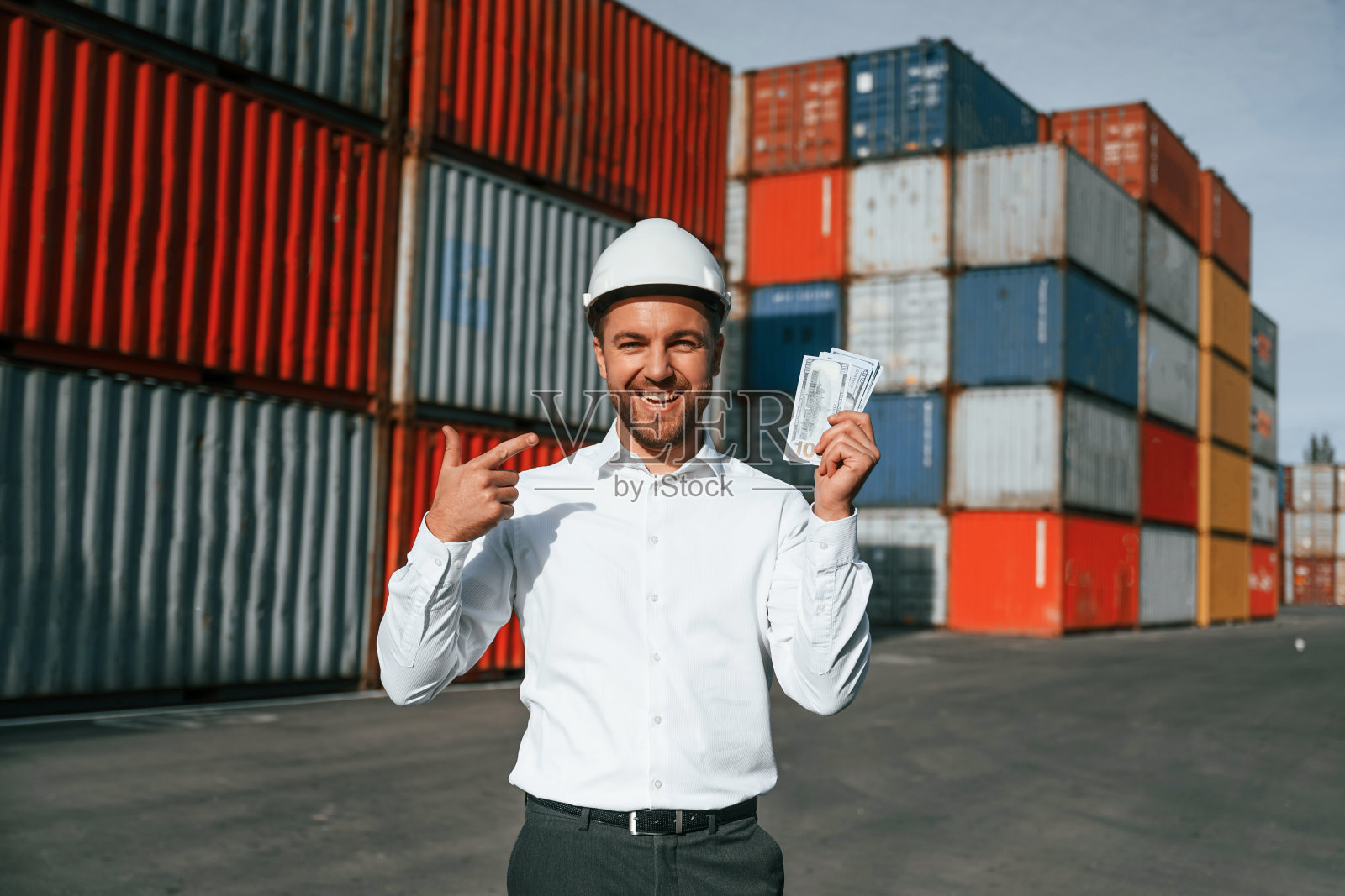 快乐的人拿着货币。男工人在集装箱的位置照片摄影图片