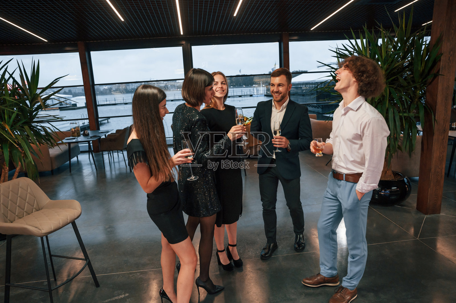对着大的全景窗。一群人穿着漂亮优雅的衣服一起在室内庆祝新年照片摄影图片